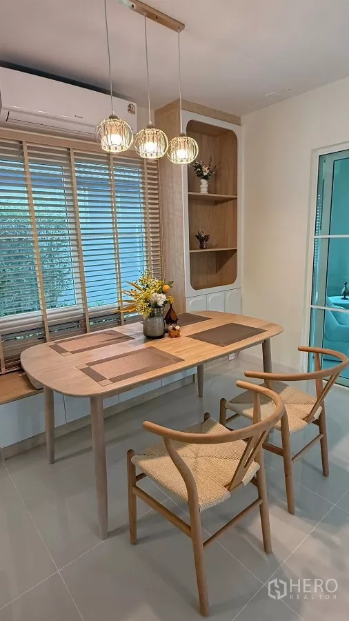 บ้าน ให้เช่าในBang Phli, Samut Prakan - มุมทานข้าวอบอุ่น โต๊ะไม้ เก้าอี้สองตัว และโคมไฟแขวน.