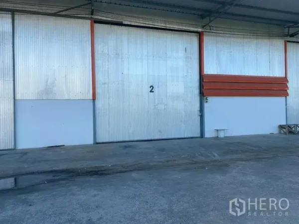 货栈 出租在Mueang Pathum Thani, Pathum Thani - 编号2的大型金属推拉门，连接带顶装卸区与混凝土硬化地面。