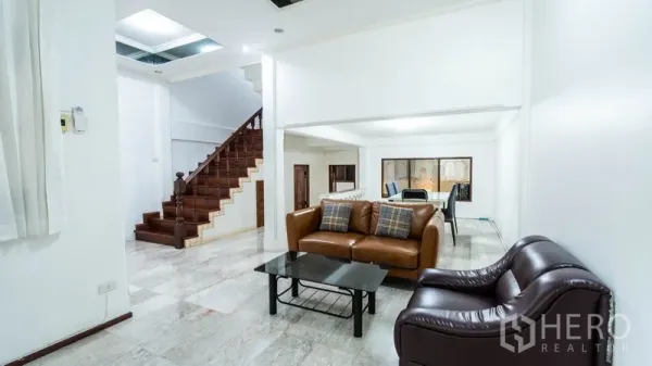 ทาวน์เฮาส์ ให้เช่าในWatthana, Bangkok - ห้องนั่งเล่นกว้างพร้อมโซฟาหนังและบันไดไม้