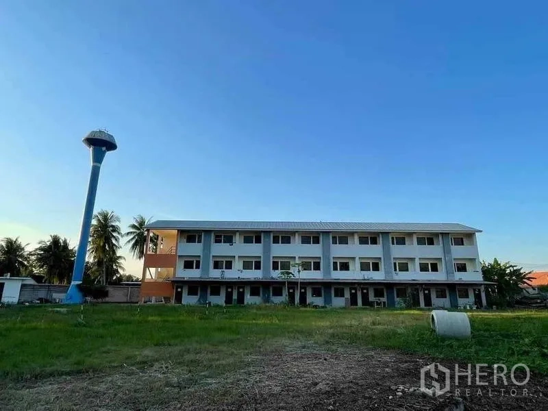 คลังสินค้า ขายในChon Buri - อาคารหอพักพนักงาน 3 ชั้น ข้างหอถังน้ำสีฟ้าและสนามหญ้า