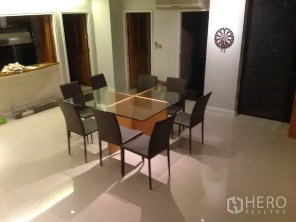 Condominium for rent in Bang Rak, Bangkok - Dining area featuring a square glass table for six beside a kitchen pass‑through.