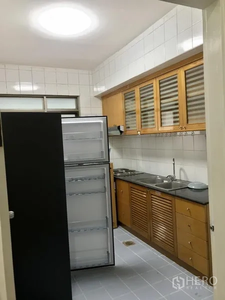 Condominium for rent in Watthana, Bangkok - Closed galley kitchen with wooden cabinets, tiled walls, double sink, and a tall refrigerator.