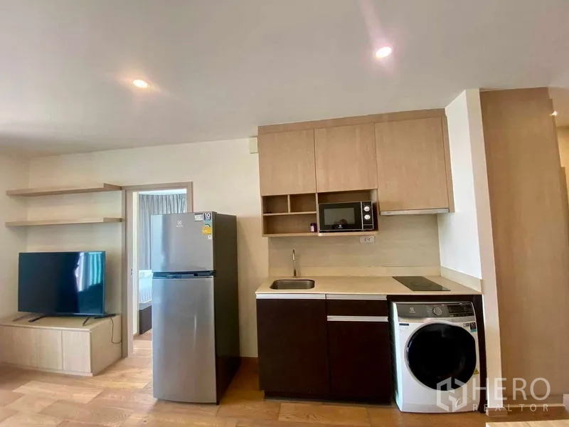 Condominium for rent or sale in Ratchathewi, Bangkok - Compact kitchen with cabinetry, cooktop, microwave, fridge and in-unit washer.