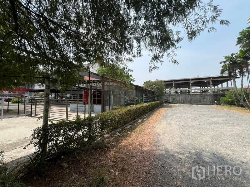 零售空间 出租在Saphan Sung, Bangkok - 宽阔的碎石停车及作业场地，绿篱与树木环绕。