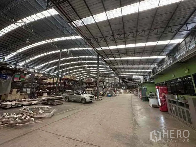 Factory for rent in Pathum Thani - Bright warehouse aisle with skylights, storage racks and an adjacent office mezzanine.