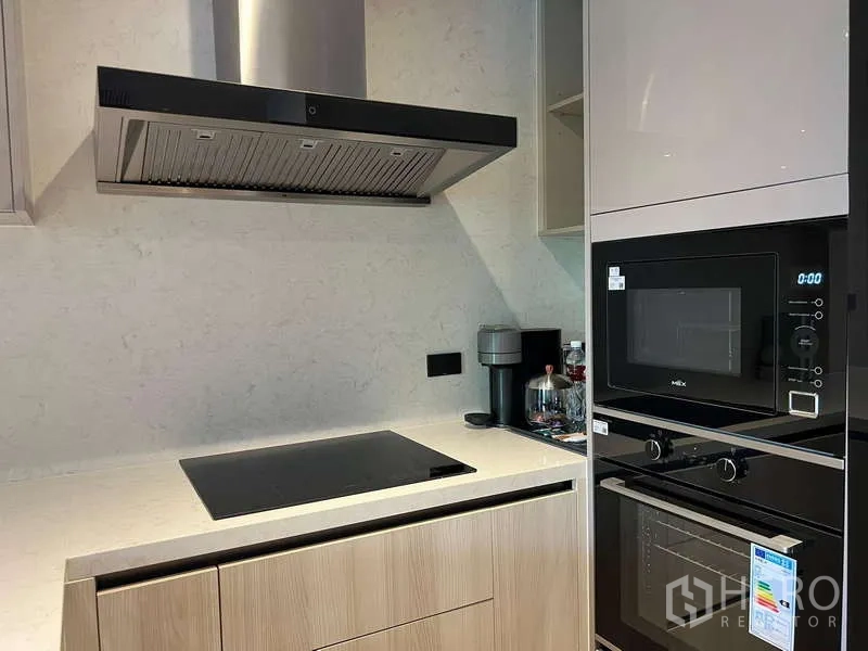 คอนโด ให้เช่าในWatthana, Bangkok - ภาพระยะใกล้ของครัว แสดงเตาไฟฟ้า เครื่องดูดควัน เตาอบ และไมโครเวฟบิวท์อิน