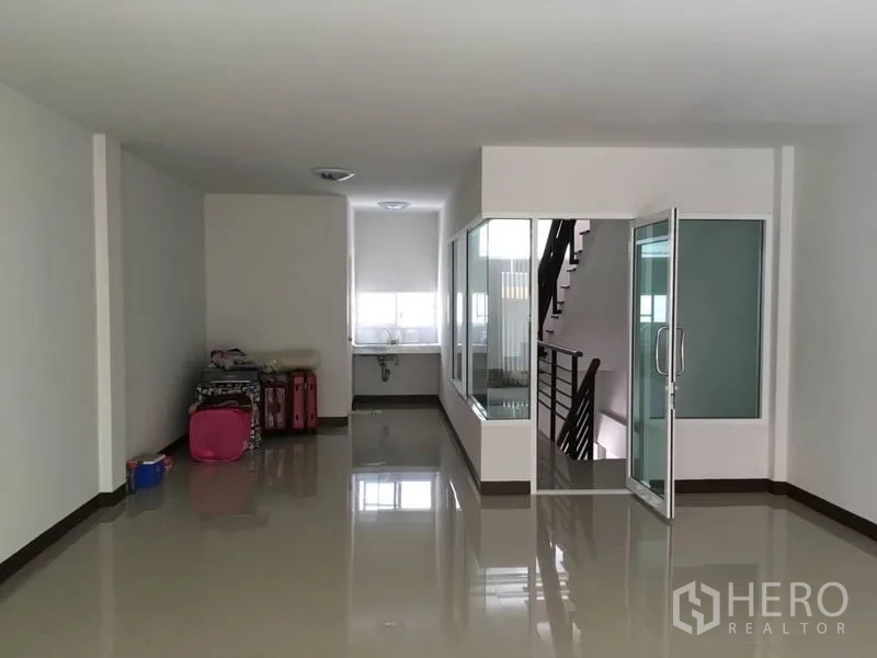 Home Office for rent in Lat Krabang, Bangkok - Open-plan ground floor with glossy tiles, glass-partitioned room, and internal staircase.