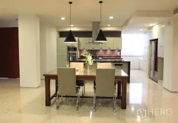 คอนโด ให้เช่าในKhlong Toei, Bangkok - ครัวแบบเปิดพร้อมไอส์แลนด์ โคมไฟแขวน และโต๊ะอาหารไม้ในคอนโดสมัยใหม่.