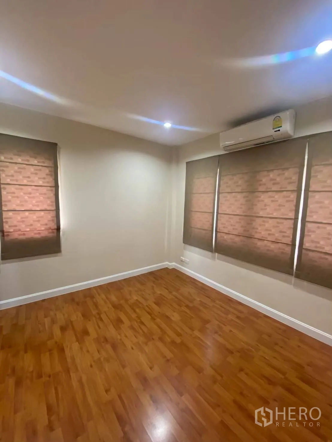 Townhouse for rent in Bang Kapi, Bangkok - Bright room with wood floors, blinds, and air conditioner.