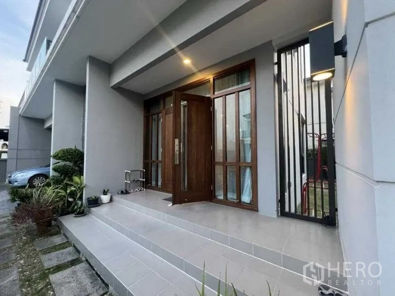 บ้าน ให้เช่าในMueang Nonthaburi, Nonthaburi - เฉลียงหน้าบ้านมีหลังคา ประตูไม้บานใหญ่ พร้อมบันไดและไฟส่อง