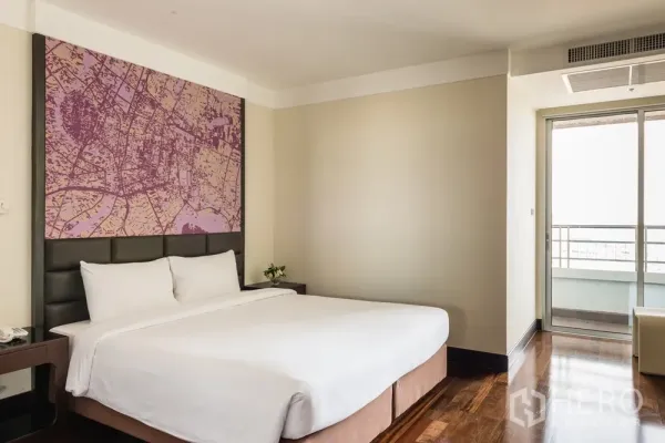 อพาร์ทเมนท์ ให้เช่าในKhlong Toei, Bangkok - ห้องนอนหลักสว่าง เตียงคิงไซส์ พนักหัวเตียงลายแผนที่ และประตูสู่ระเบียง