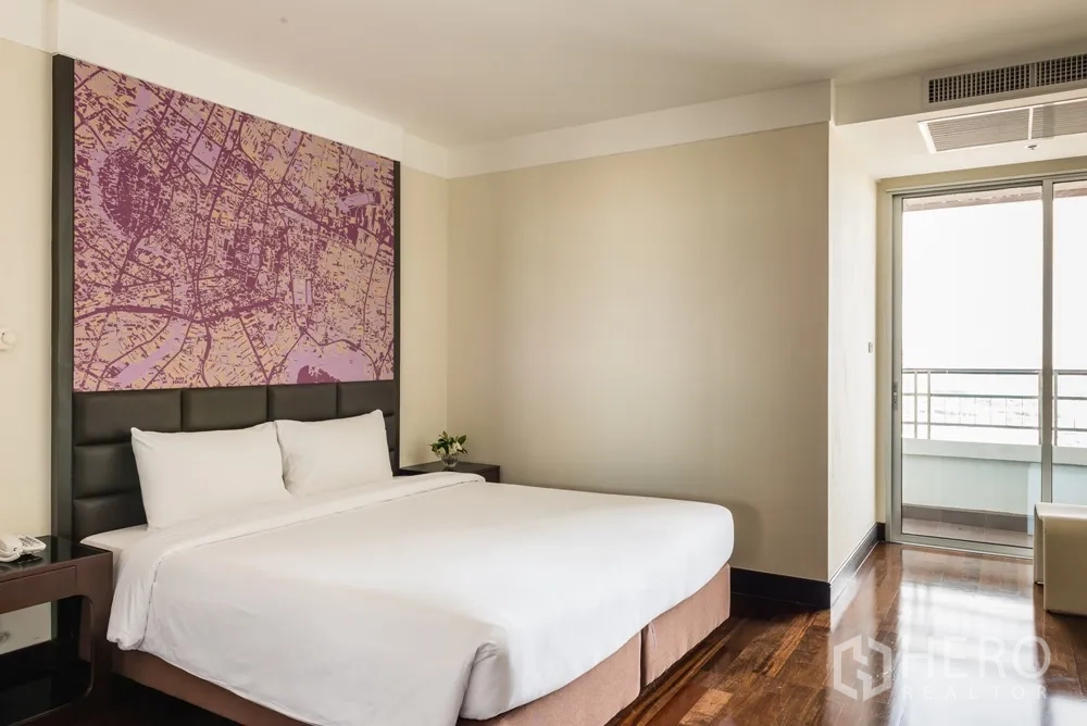 อพาร์ทเมนท์ ให้เช่าในKhlong Toei, Bangkok - ห้องนอนหลักสว่าง เตียงคิงไซส์ พนักหัวเตียงลายแผนที่ และประตูสู่ระเบียง