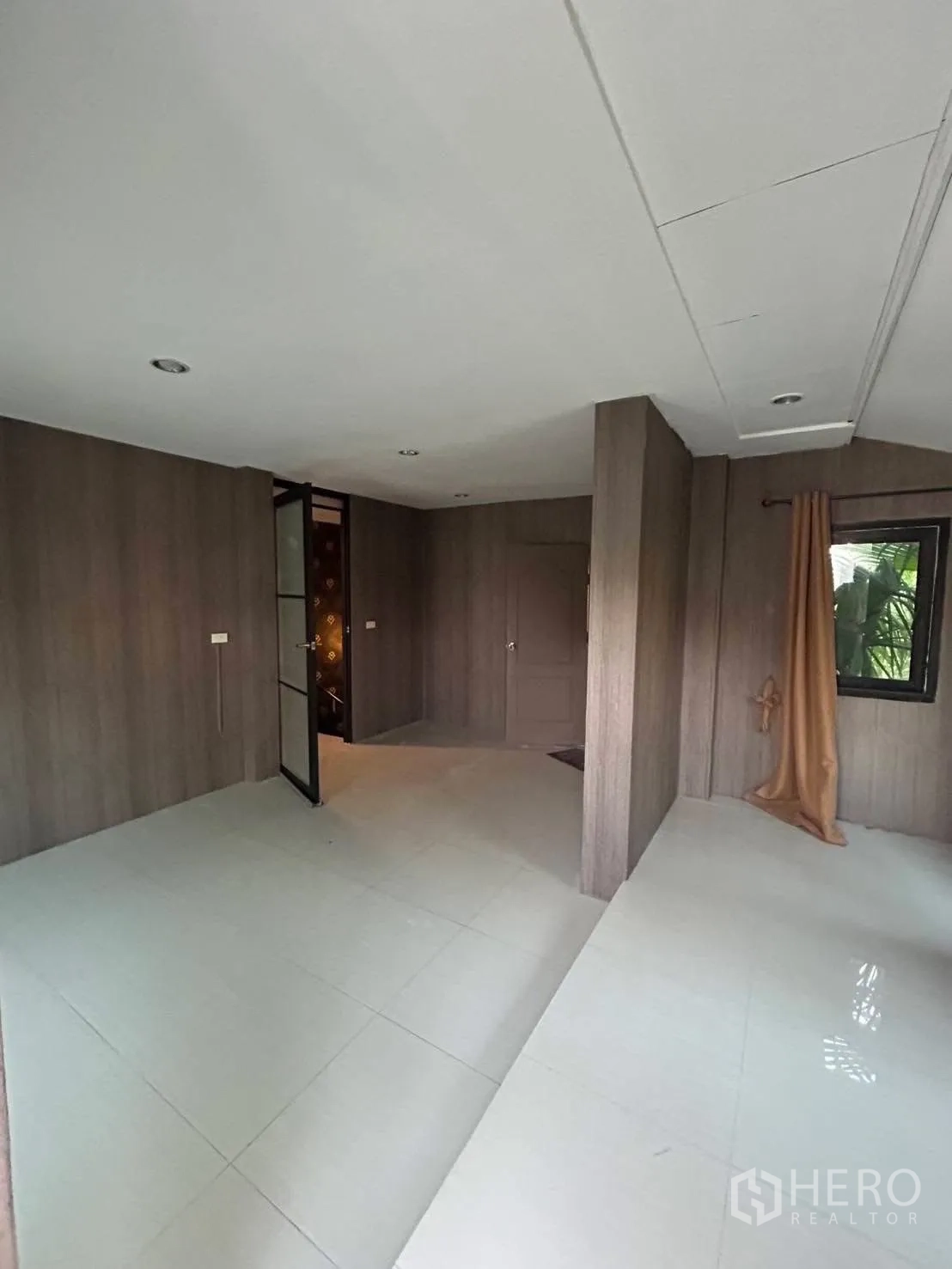 Detached House for rent or sale in Wang Thonglang, Bangkok - Multi-purpose room with wood wall cladding, pale tile floors and corner window with curtain.