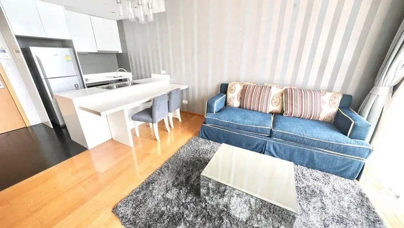 公寓 出租或出售在Watthana, Bangkok - 开放式客餐厅，蓝色沙发、吧台餐桌与木地板。