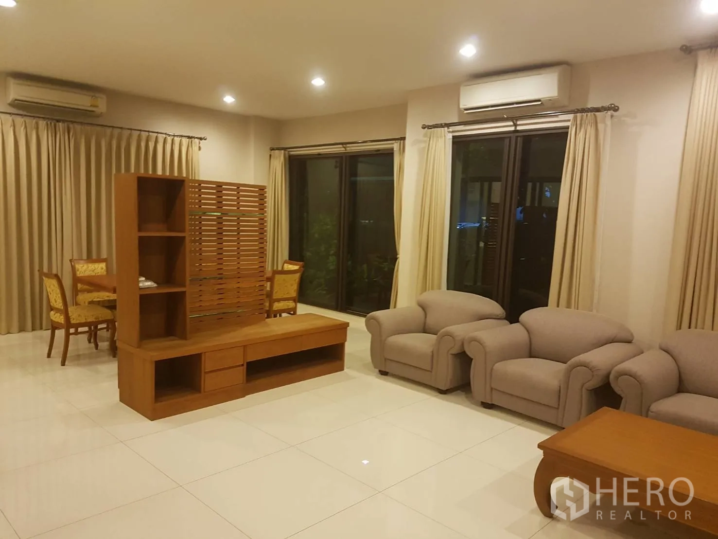 ทาวน์เฮาส์ ให้เช่าในBang Kapi, Bangkok - ห้องนั่งเล่นกว้าง พื้นกระเบื้อง ชุดโซฟาสีเบจ ตู้ทีวีไม้ และประตูกระจกบานเลื่อน