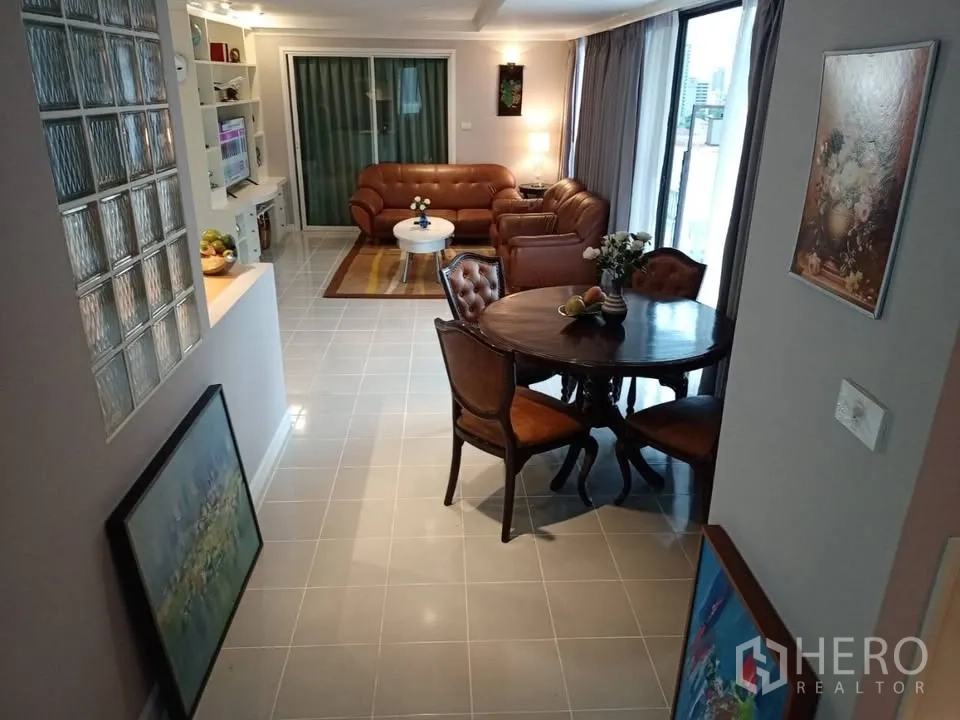 公寓 for rent in Watthana, Bangkok - 餐区为圆形木桌与椅子，旁为推拉门通向阳台。