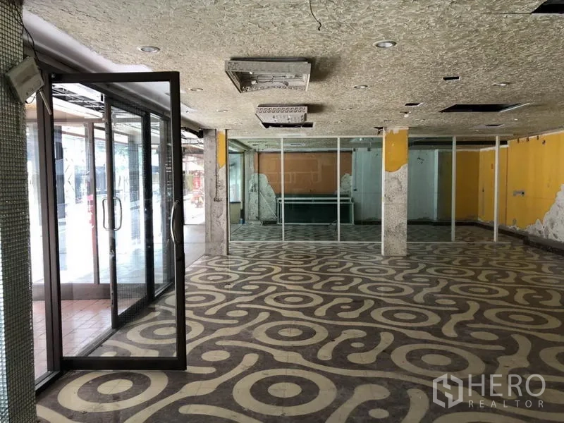 零售空间 出租在Khlong Toei, Bangkok - 宽敞展厅区，带玻璃隔断与结构立柱。