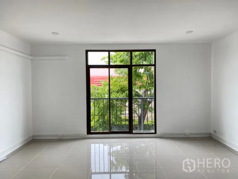 Home Office for rent in Wang Thonglang, Bangkok - Bright room with floor-to-ceiling window and small balcony railing facing trees.