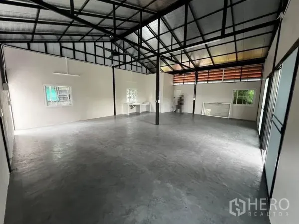 Warehouse for rent in Suan Luang, Bangkok - Spacious clear-span warehouse showing windows, work counter and steel frame ceiling.