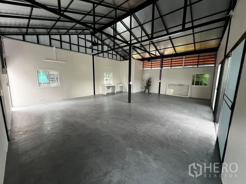 Warehouse for rent in Suan Luang, Bangkok - Spacious clear-span warehouse showing windows, work counter and steel frame ceiling.