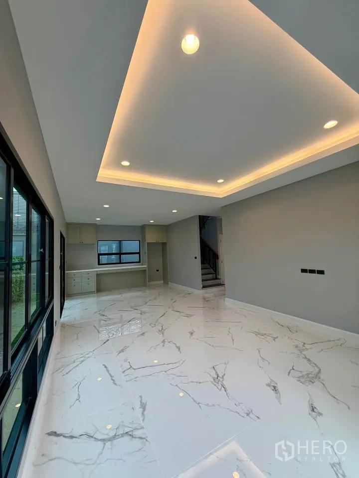 Detached House for rent in Don Mueang, Bangkok - Open-plan living and dining area with cove lighting and sliding glass doors.