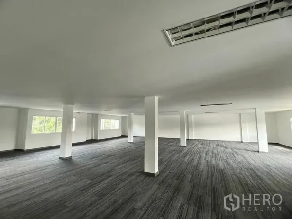 零售空间 出租在Huai Khwang, Bangkok - 明亮的开间零售室内，多根立柱与灰色地毯，天花荧光灯板覆盖整个空间。