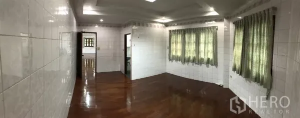 Home Office for rent in Dusit, Bangkok - Open-plan floor with multiple windows, curtains, and glossy wood flooring ideal for workspaces.