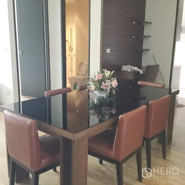 คอนโด ให้เช่าในWatthana, Bangkok - มุมรับประทานอาหาร 4 ที่นั่ง โต๊ะกระจก ทางเข้าห้องน้ำ และผนังไม้ตกแต่งพร้อมชั้นวาง