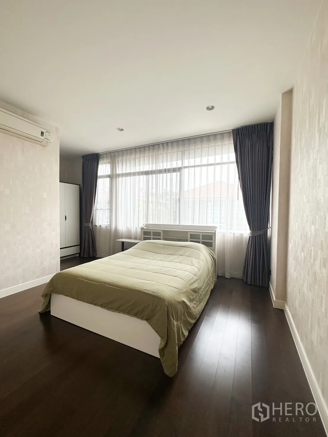 Detached House for rent or sale in Bang Kapi, Bangkok - Bright bedroom with large windows, sheer curtains and wood flooring.