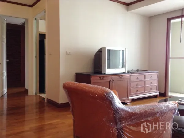 คอนโด ให้เช่าหรือขายในWatthana, Bangkok - มุมนั่งเล่นพร้อมตู้วางทีวีสไตล์คลาสสิก เก้าอี้ และประตูกระจกสู่ระเบียง