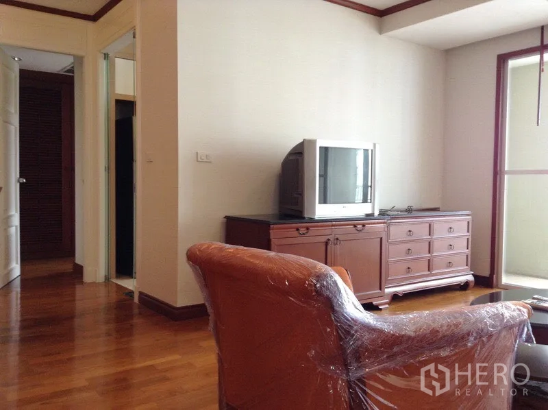 คอนโด ให้เช่าหรือขายในWatthana, Bangkok - มุมนั่งเล่นพร้อมตู้วางทีวีสไตล์คลาสสิก เก้าอี้ และประตูกระจกสู่ระเบียง