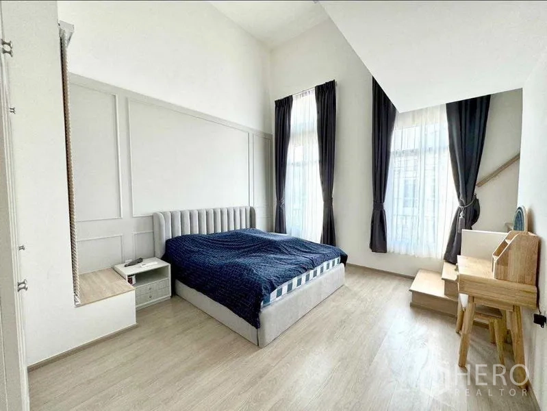 联排别墅 出租或出售在Prawet, Bangkok - 主卧挑高空间，落地窗、浅木地板与书桌。