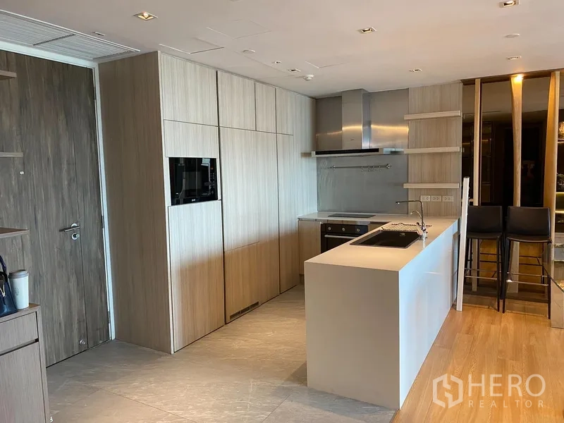 Condominium for rent in Yan Nawa, Bangkok - Contemporary kitchen featuring an island sink, built-in oven and light wood cabinetry.
