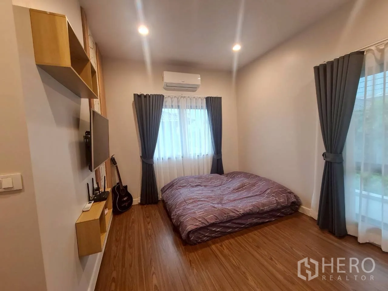 บ้าน ให้เช่าหรือขายในLam Luk Ka, Pathum Thani - ห้องนอนที่สาม ปูที่นอนพื้น หน้าต่างสองด้าน ทีวีติดผนัง และกีตาร์