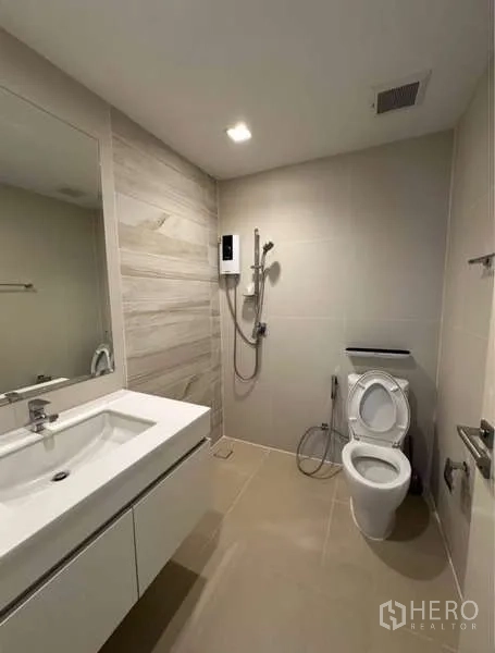 联排别墅 出租在Lat Phrao, Bangkok - 中性色浴室，含洗手台、坐便器和步入式淋浴及热水器。