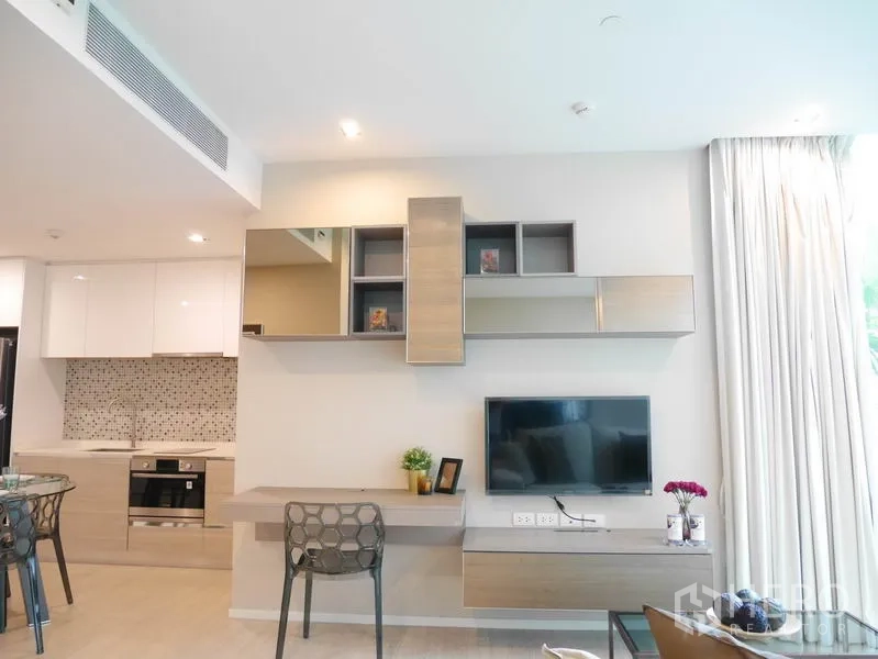 Condominium for rent or sale in Watthana, Bangkok - Built-in media wall with TV and storage beside a light-filled kitchenette and dining nook.