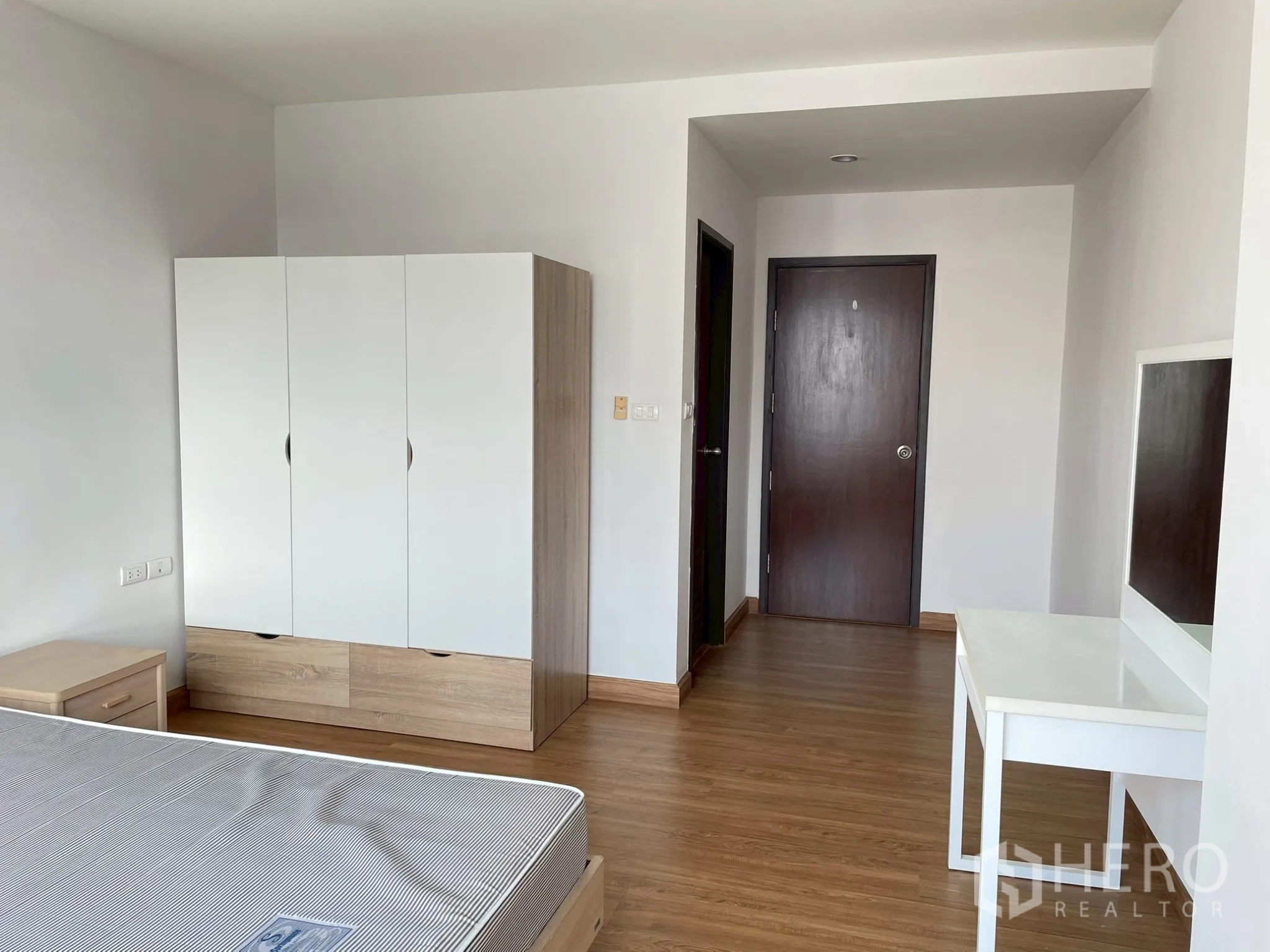 Apartment for rent in Khlong Toei, Bangkok - Bedroom view of wardrobe, dressing table, and hallway door.