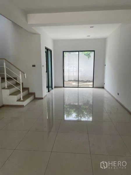 Townhouse for sale in Bueng Kum, Bangkok - Open-plan living area with glossy tile floors, staircase and sliding glass doors.