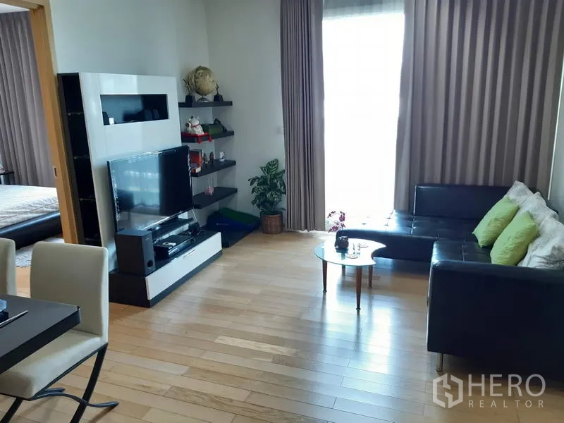 คอนโด ให้เช่าในKhlong Toei, Bangkok - ห้องนั่งเล่นสว่าง โซฟาหนังรูปตัวแอล ชุดทีวี ชั้นลอย และผ้าม่านเต็มบาน