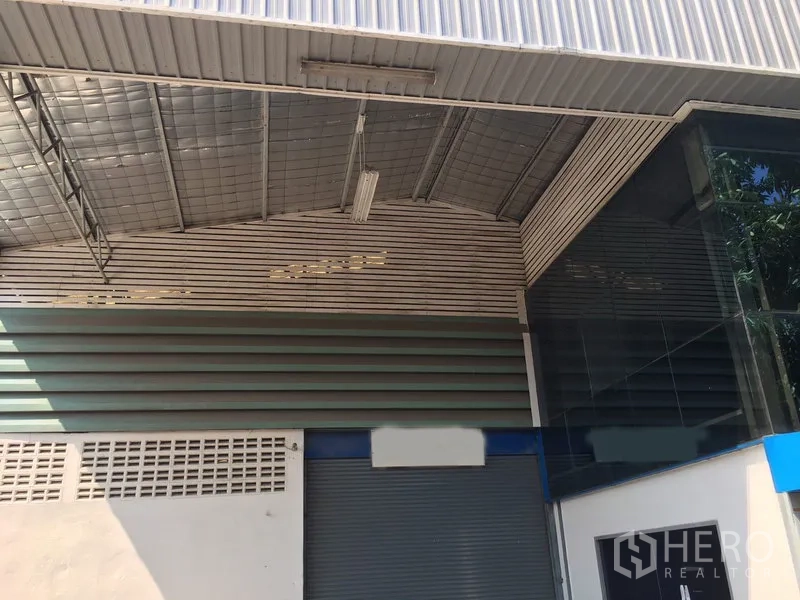 Warehouse for rent in Suan Luang, Bangkok - Covered loading area with large roller shutter door and metal roof.