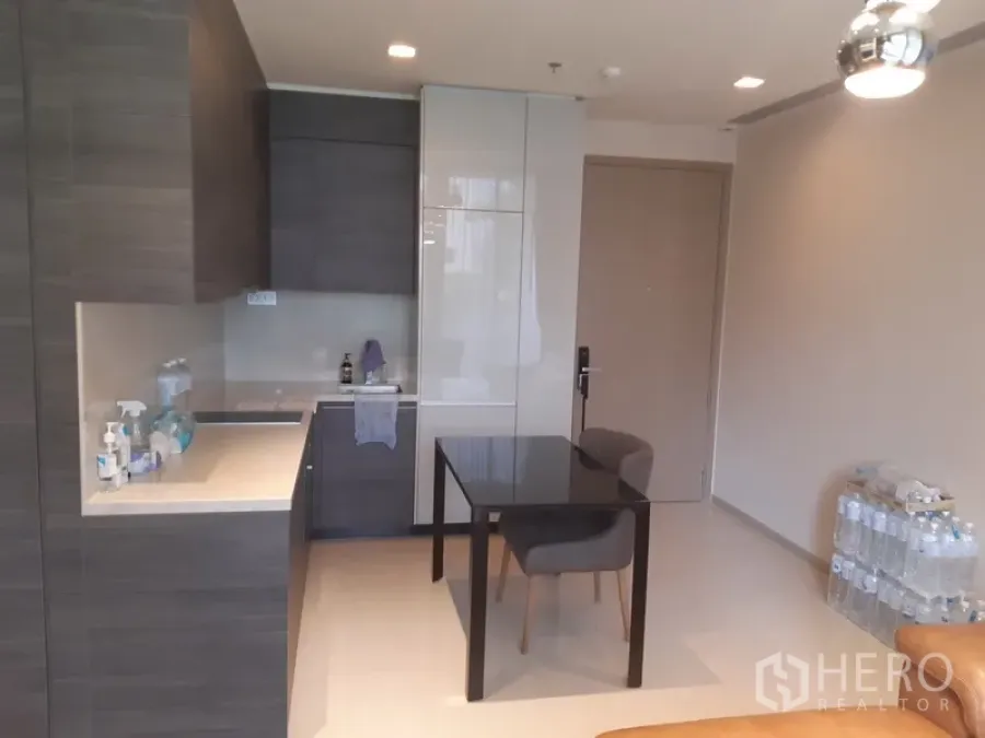 Condominium for rent or sale in Watthana, Bangkok - Modern kitchenette with grey cabinetry, stone countertop and a compact dining table for two.