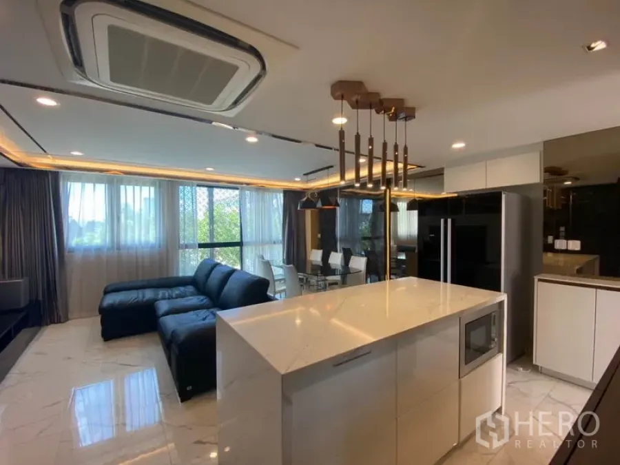 ทาวน์เฮาส์ ขายในYan Nawa, Bangkok - พื้นที่นั่งเล่นแบบโอเพ่นพร้อมพื้นหินอ่อน โซฟาหนังสีดำ และครัวไอส์แลนด์ภายใต้โคมไฟแขวนและหน้าต่างบานใหญ่