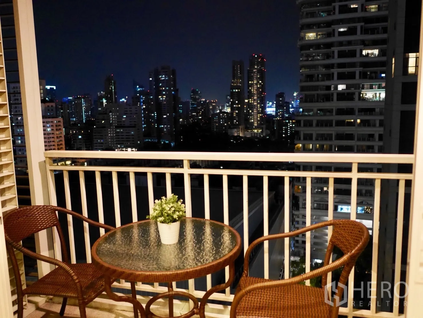 คอนโด ให้เช่าในWatthana, Bangkok - ระเบียงพร้อมโต๊ะหวายและเก้าอี้ มองเห็นวิวสกายไลน์กรุงเทพฯ ยามค่ำคืน
