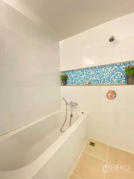 คอนโด ให้เช่าหรือขายในPhra Khanong, Bangkok - ห้องน้ำสว่างพร้อมอ่างอาบน้ำ กระเบื้องขาว แต้มโมเสกสีน้ำเงินและต้นไม้กระถาง