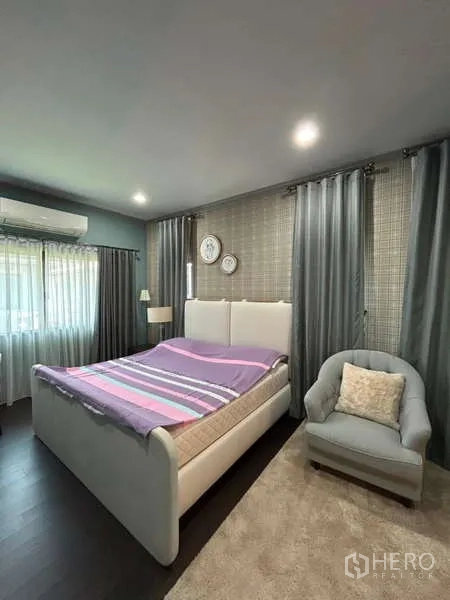 独立式住宅 出租在Bang Kapi, Bangkok - 明亮卧室，白色软包床、单人沙发与灰色窗帘。