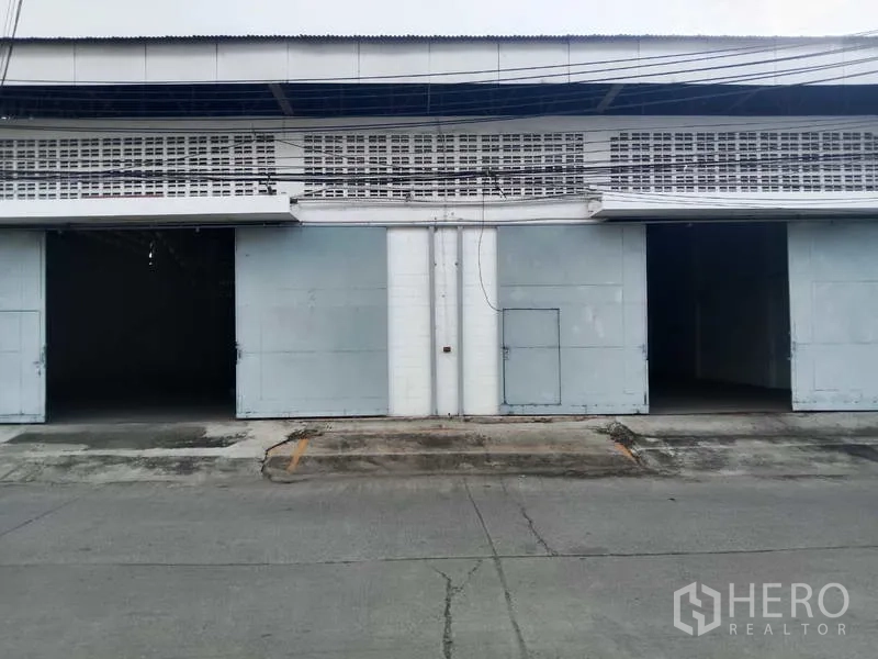 工厂 出租在Samut Prakan - 工厂外立面，两个宽大的金属推拉门与装卸区