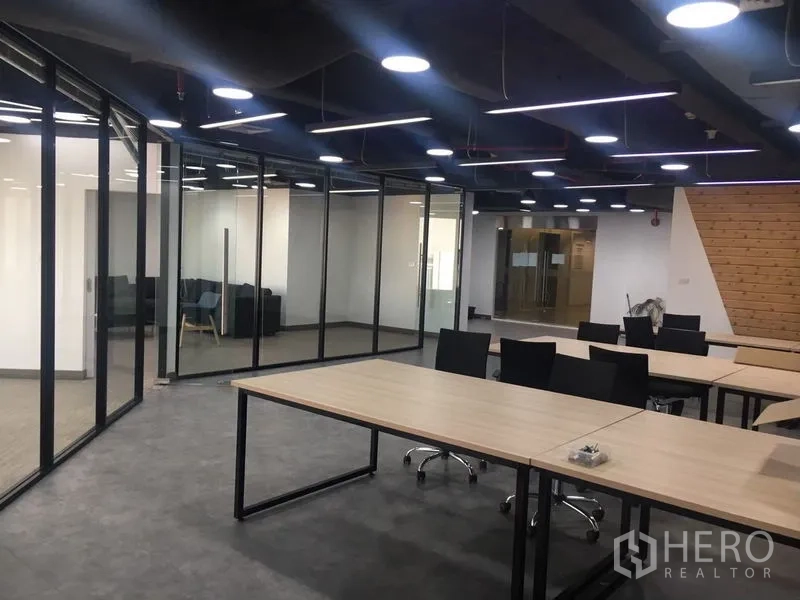 Office Space for rent in Sathon, Bangkok - Open-plan office with glass partitions forming rooms and bright suspended LED light strips.