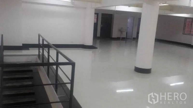 Shophouse for rent in Sathon, Bangkok - Wide commercial floor view with white columns, safety railing and bright overhead lighting.