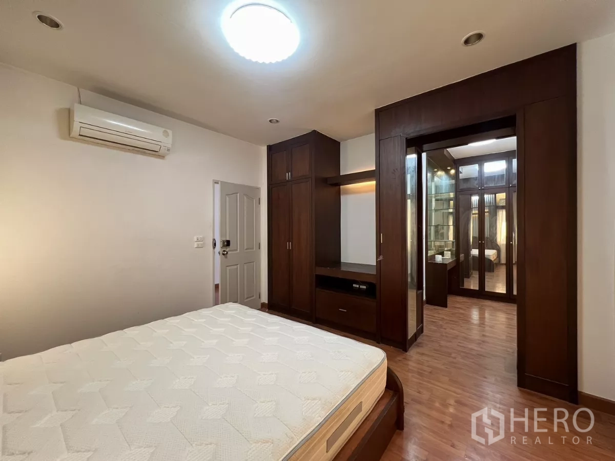 Detached House for rent in Bang Kapi, Bangkok - Master bedroom with built-in wardrobes and walk-in closet entrance.