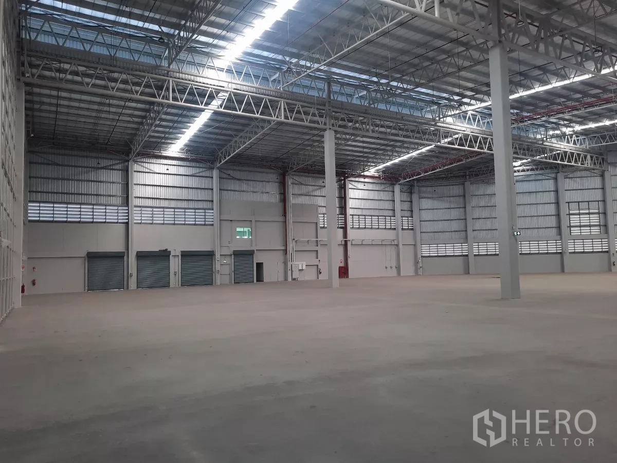 Factory for rent in Bang Lamung, Chon Buri - Large storage area with several roller shutters and exit doors.